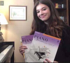 Online Piano Student holding Piano Books